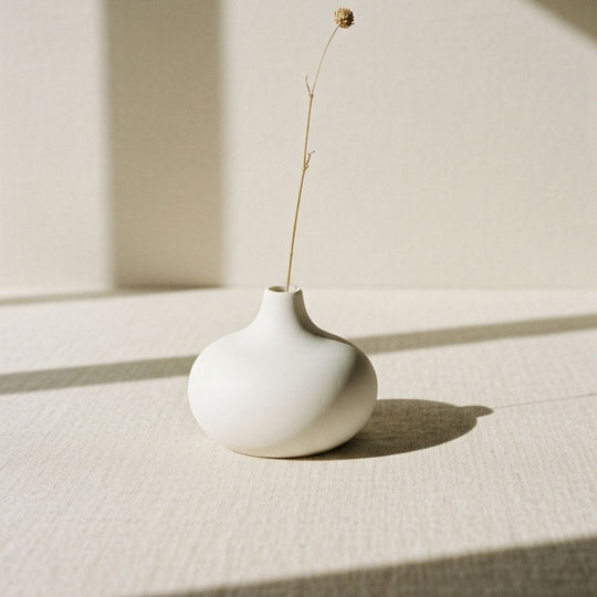 Small ceramic vase with single dried pampas grass stem on windowsill